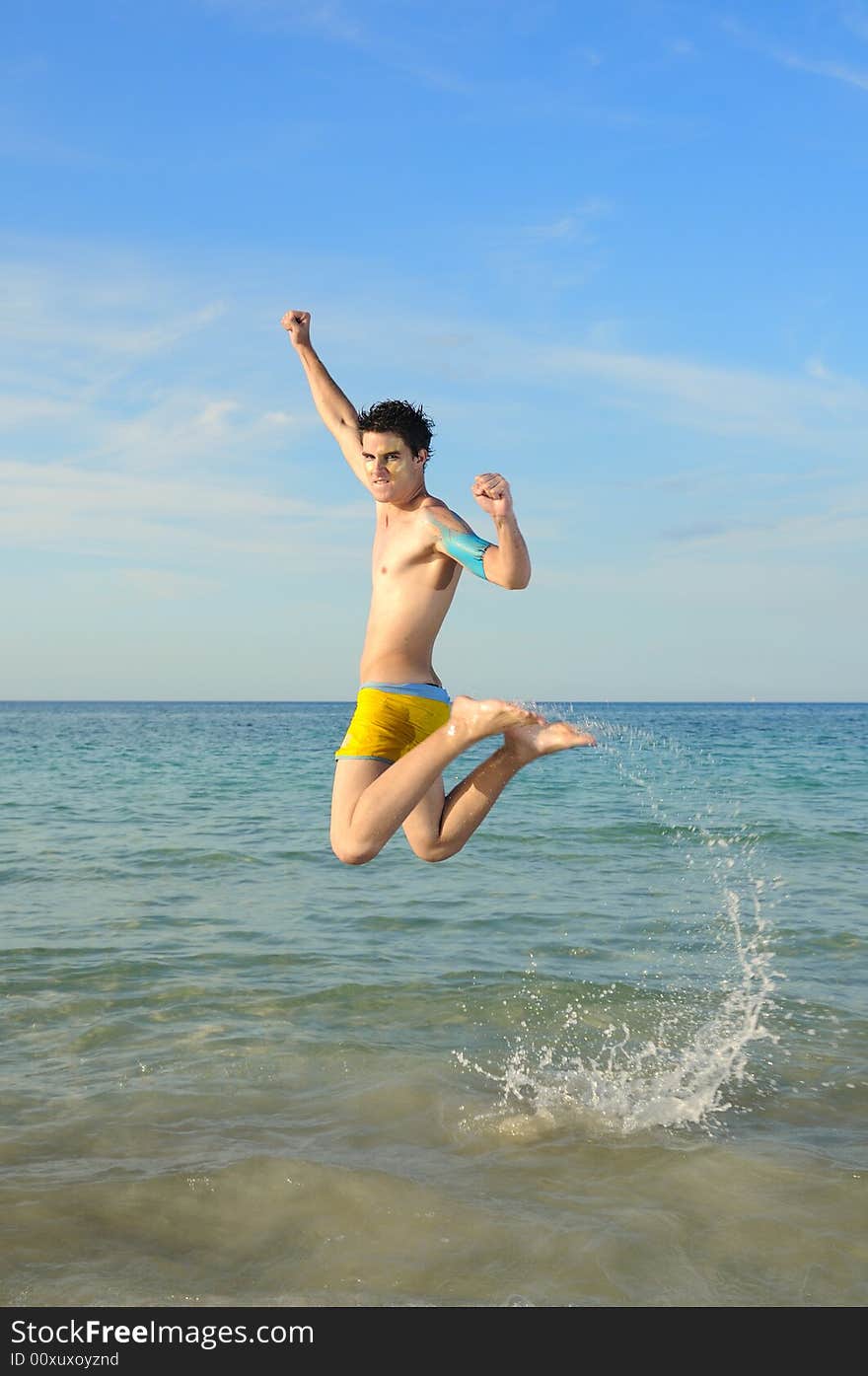 Portrait of young male jumping of joy against tropical beach background. Portrait of young male jumping of joy against tropical beach background