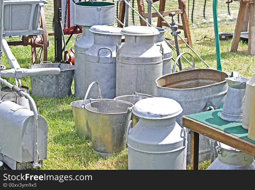 Old galvanised farm milk churns and buckets sitting on the grass. Old galvanised farm milk churns and buckets sitting on the grass