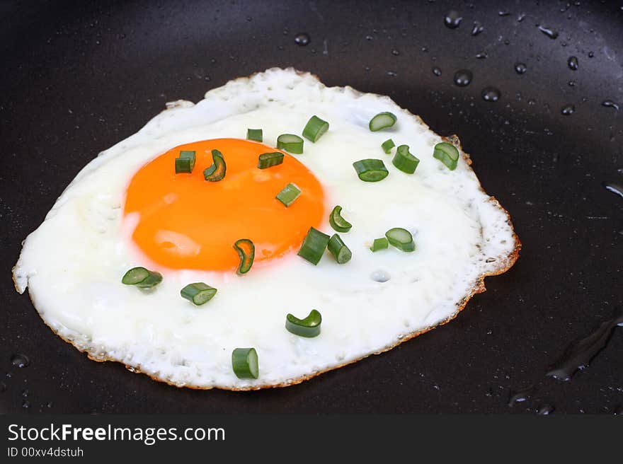 A close up for a egg with chive in a frying pan. A close up for a egg with chive in a frying pan