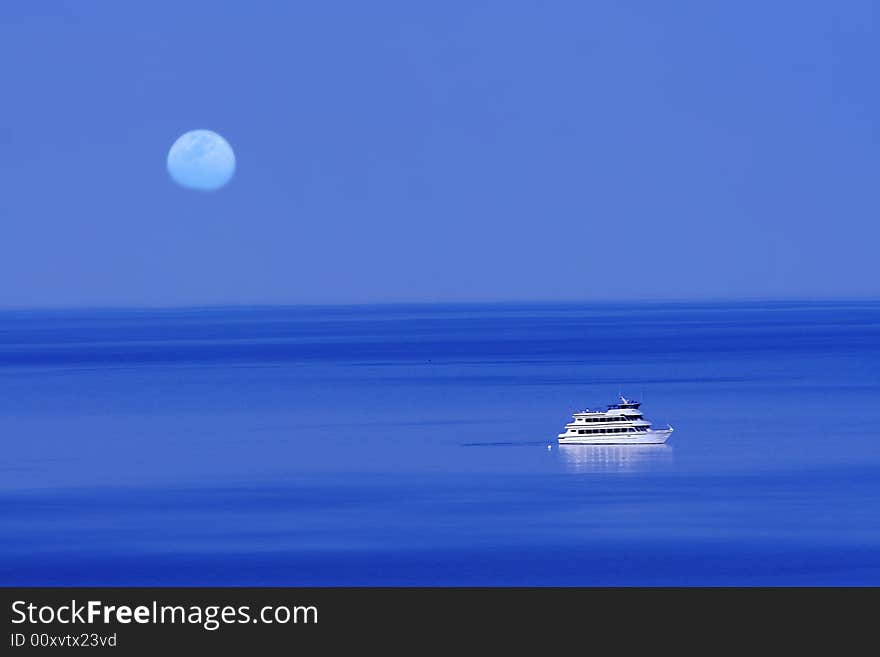 Moon over blue lake with boat