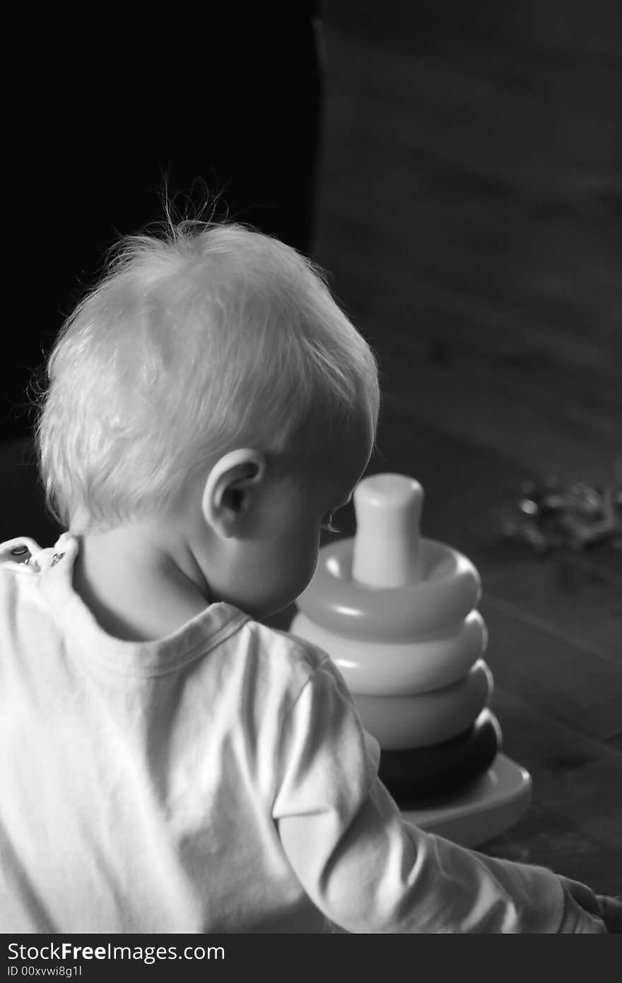 Black and white portrait of a young baby playing with some toys on the floor. Black and white portrait of a young baby playing with some toys on the floor