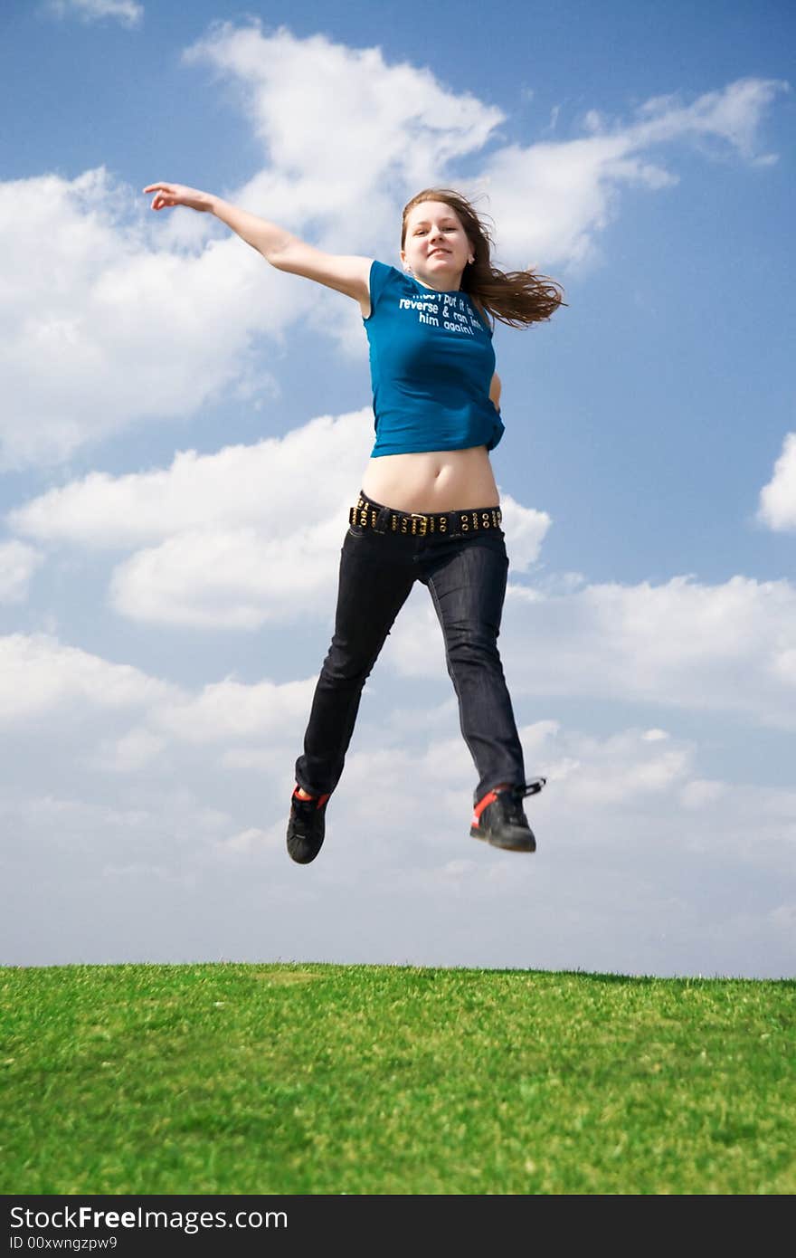 The happy jumping girl on a background of the blue sky