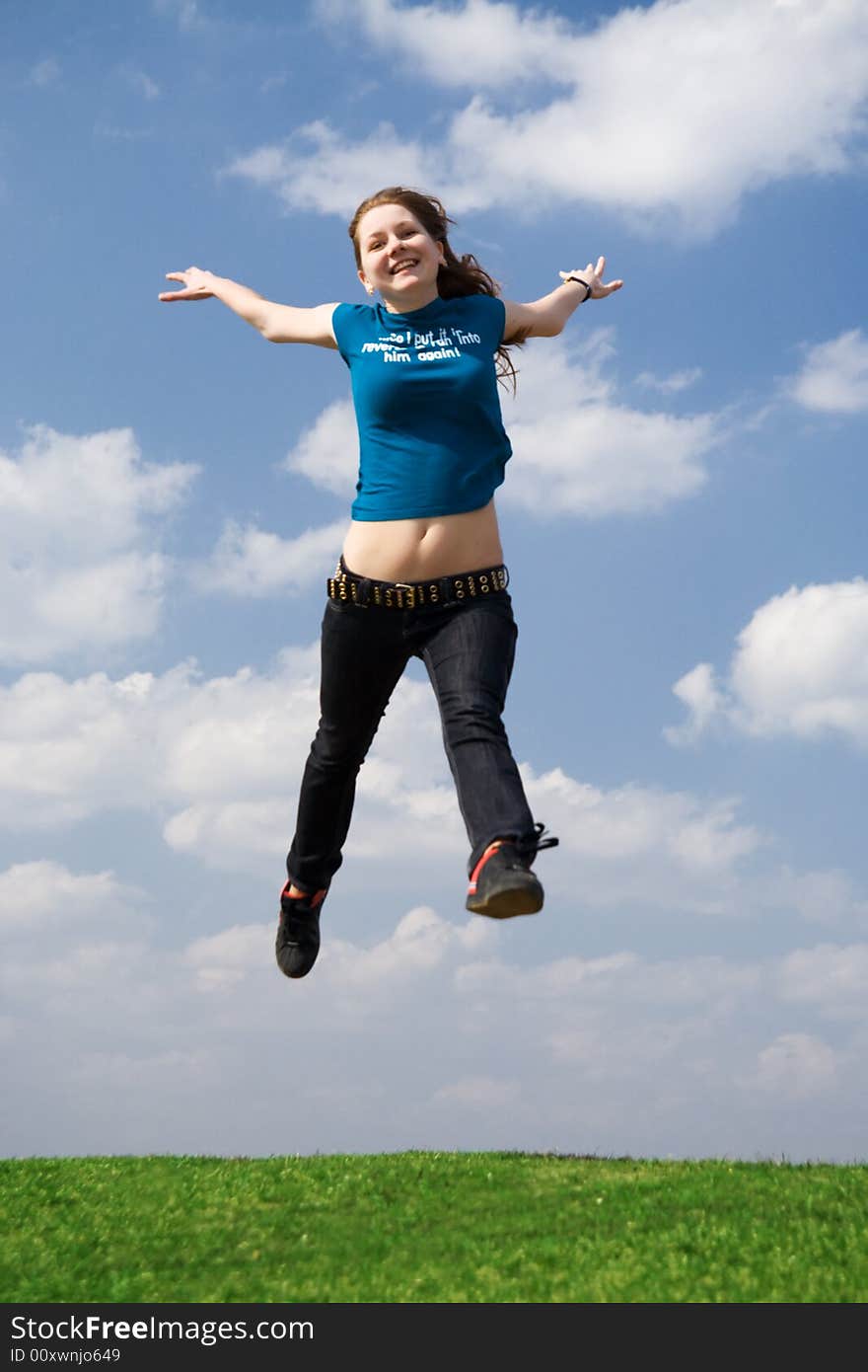 The happy jumping girl on a background of the blue sky