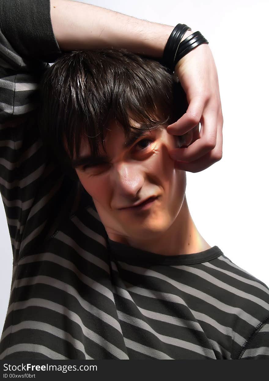 A portrait about a trendy cute young man who is smiling and he is scratching himself reverse. He is wearing a striped t-shirt. A portrait about a trendy cute young man who is smiling and he is scratching himself reverse. He is wearing a striped t-shirt.