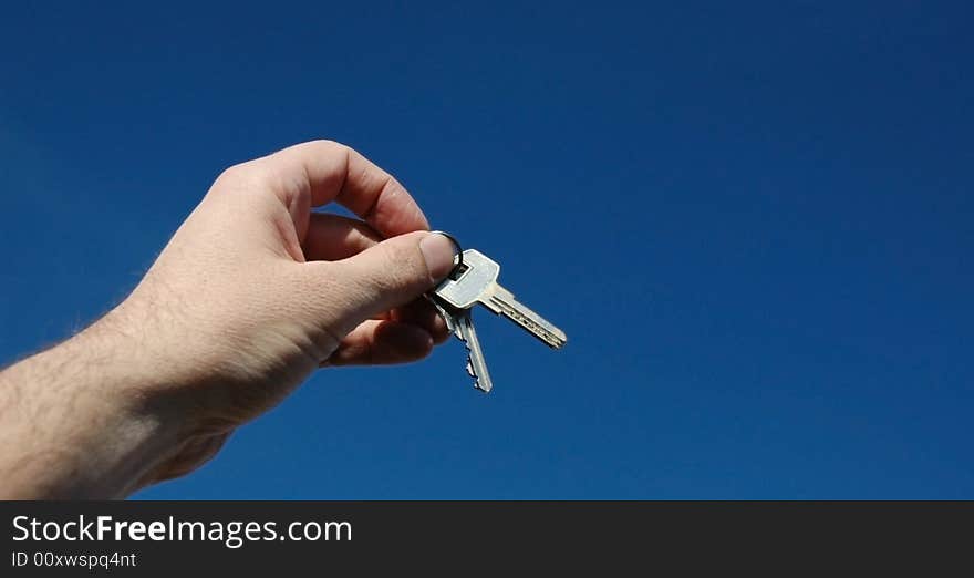 Keys in a hand on a background of the sky