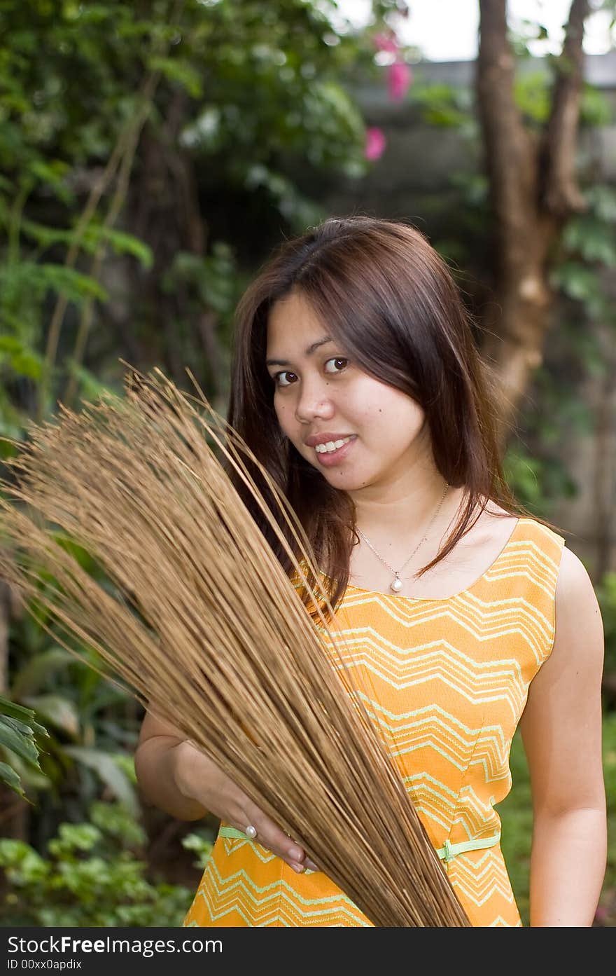 A beautiful lady holding stick broom while cleaning garden. A beautiful lady holding stick broom while cleaning garden