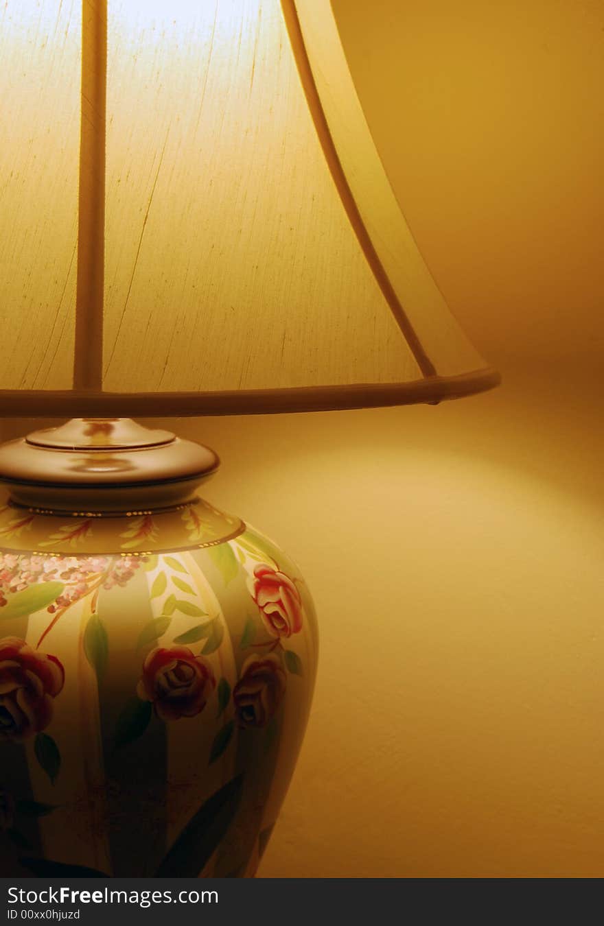 A traditional painted lamp with flowers, illuminating the yellow wall behind it. A traditional painted lamp with flowers, illuminating the yellow wall behind it.