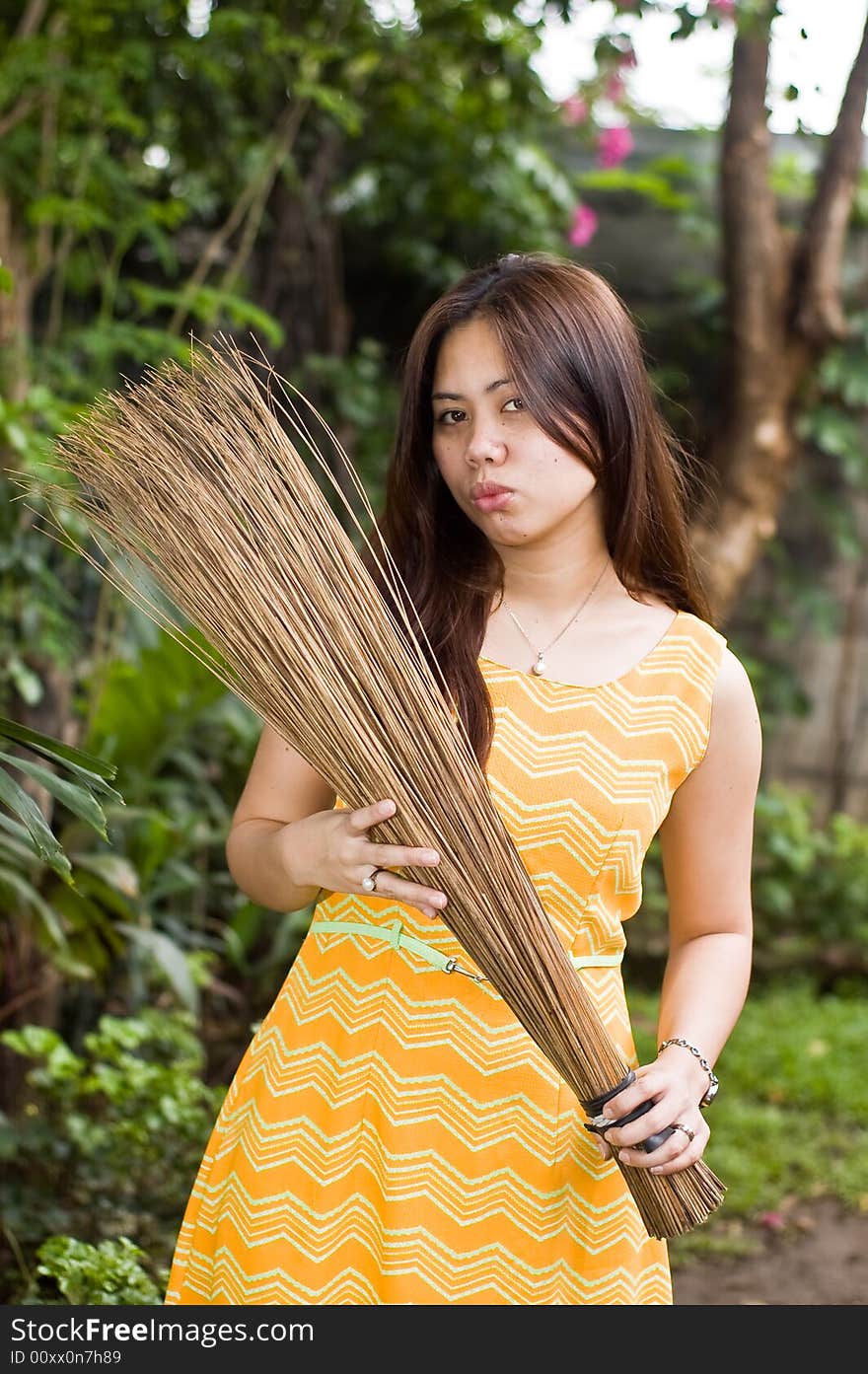 A beautiful lady holding stick broom while cleaning garden. A beautiful lady holding stick broom while cleaning garden