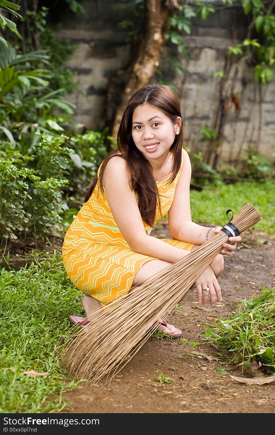 Gorgeous lady holding a broom crouched on garden. Gorgeous lady holding a broom crouched on garden