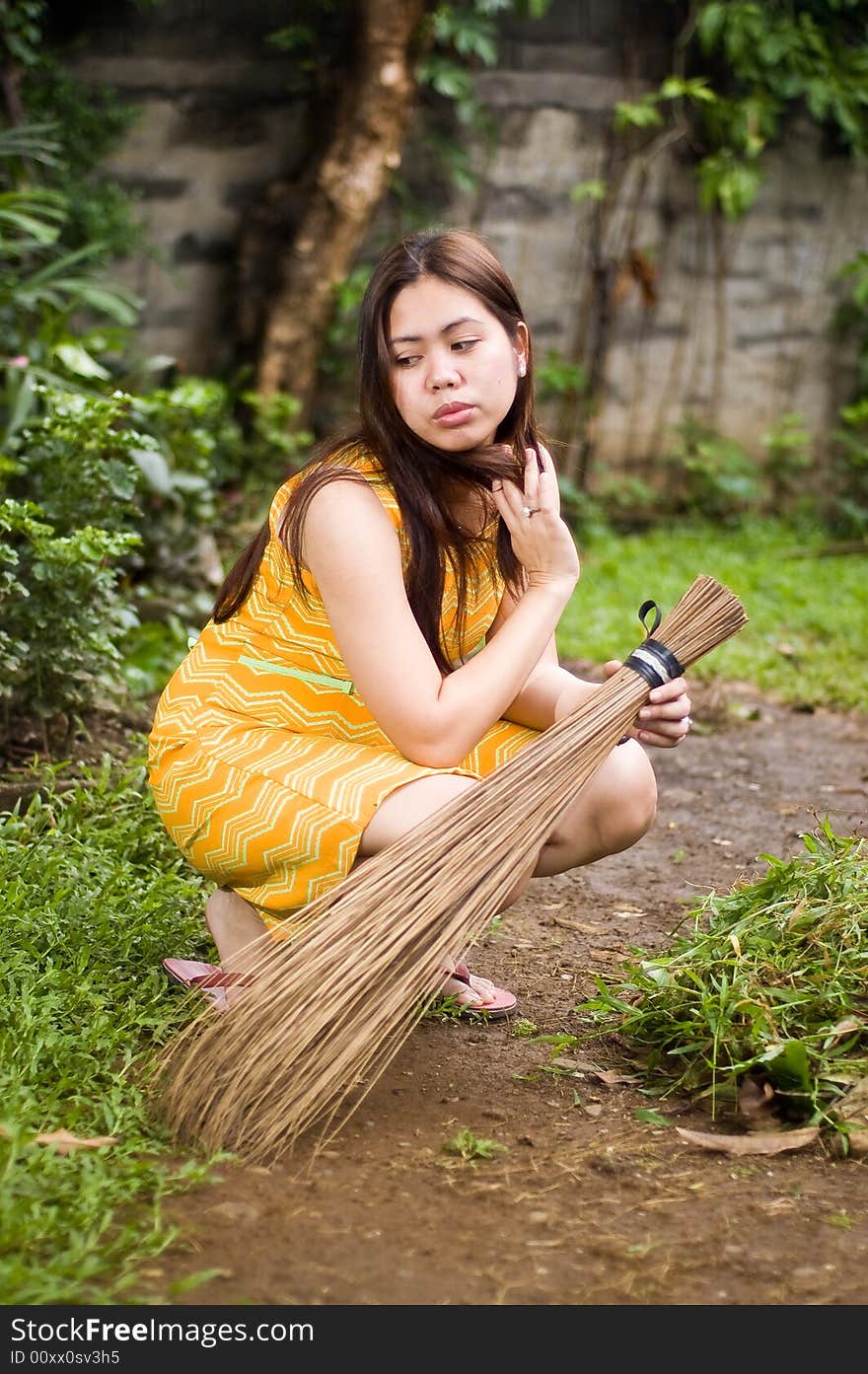 Gorgeous lady holding a broom crouched on garden. Gorgeous lady holding a broom crouched on garden