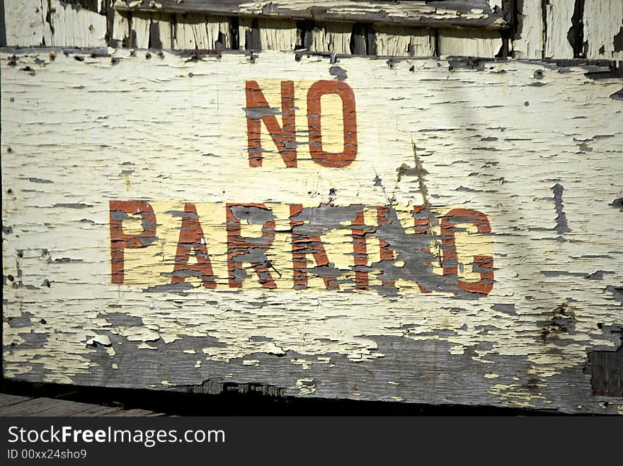 Old weathered no parking warning painted on old rotting peeling doors in portland maine