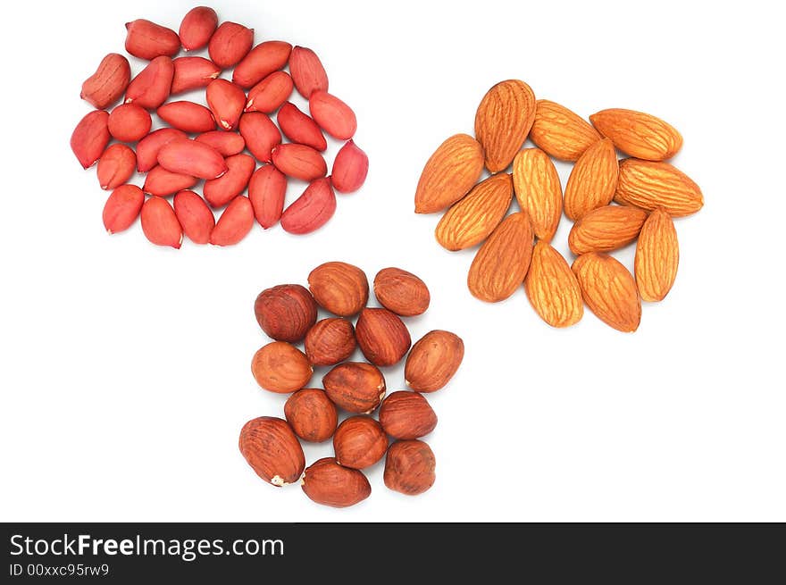 Three small heaps of hazel, almond and peanut on the white background. Three small heaps of hazel, almond and peanut on the white background