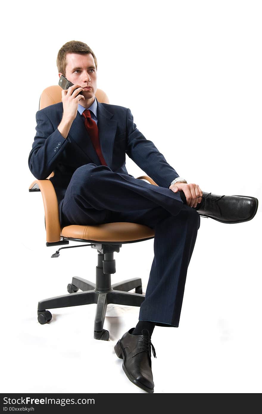 Businessman sitting on an armchair with cell phone. Isolated