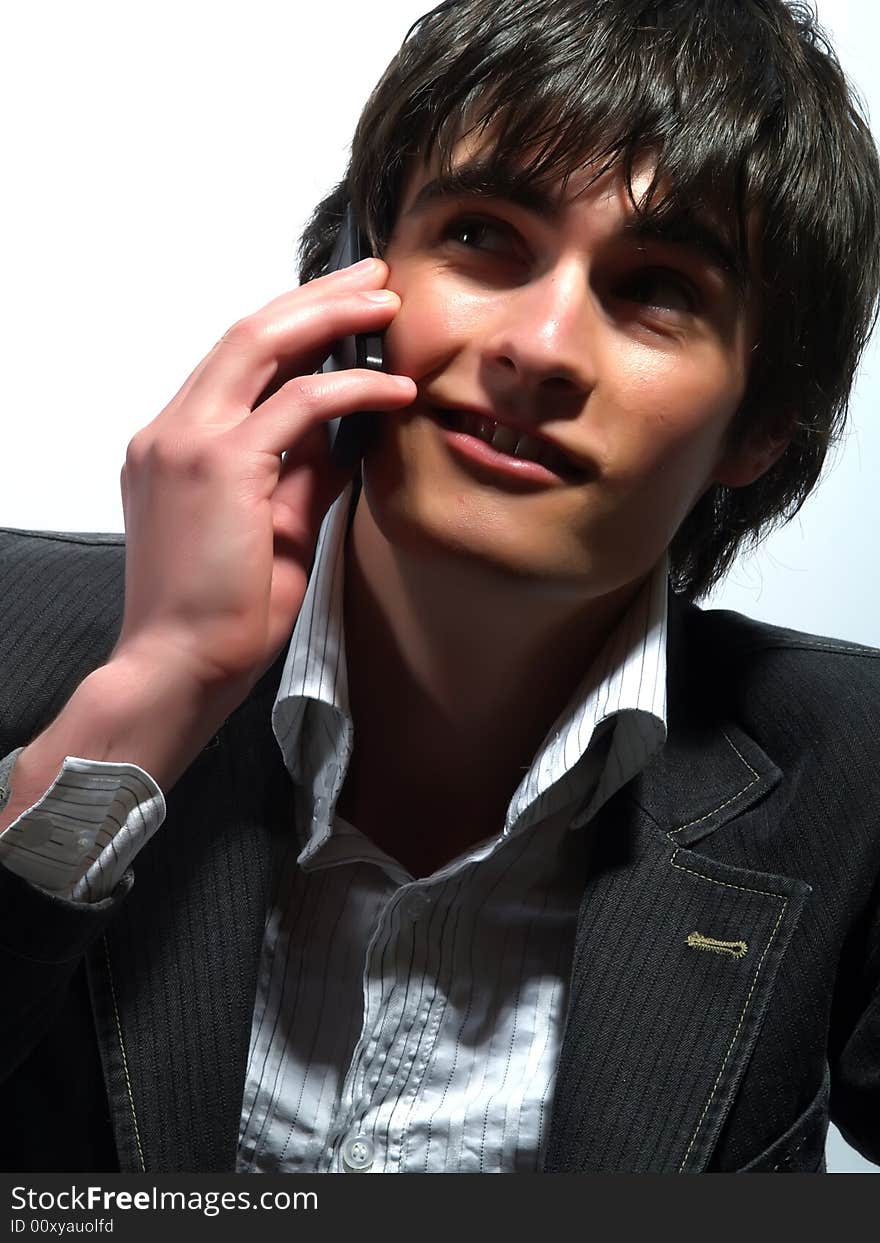 A portrait about a trendy attractive guy who is smiling and he is ringing up somebody. He is wearing a white shirt and a stylish black suit. A portrait about a trendy attractive guy who is smiling and he is ringing up somebody. He is wearing a white shirt and a stylish black suit.