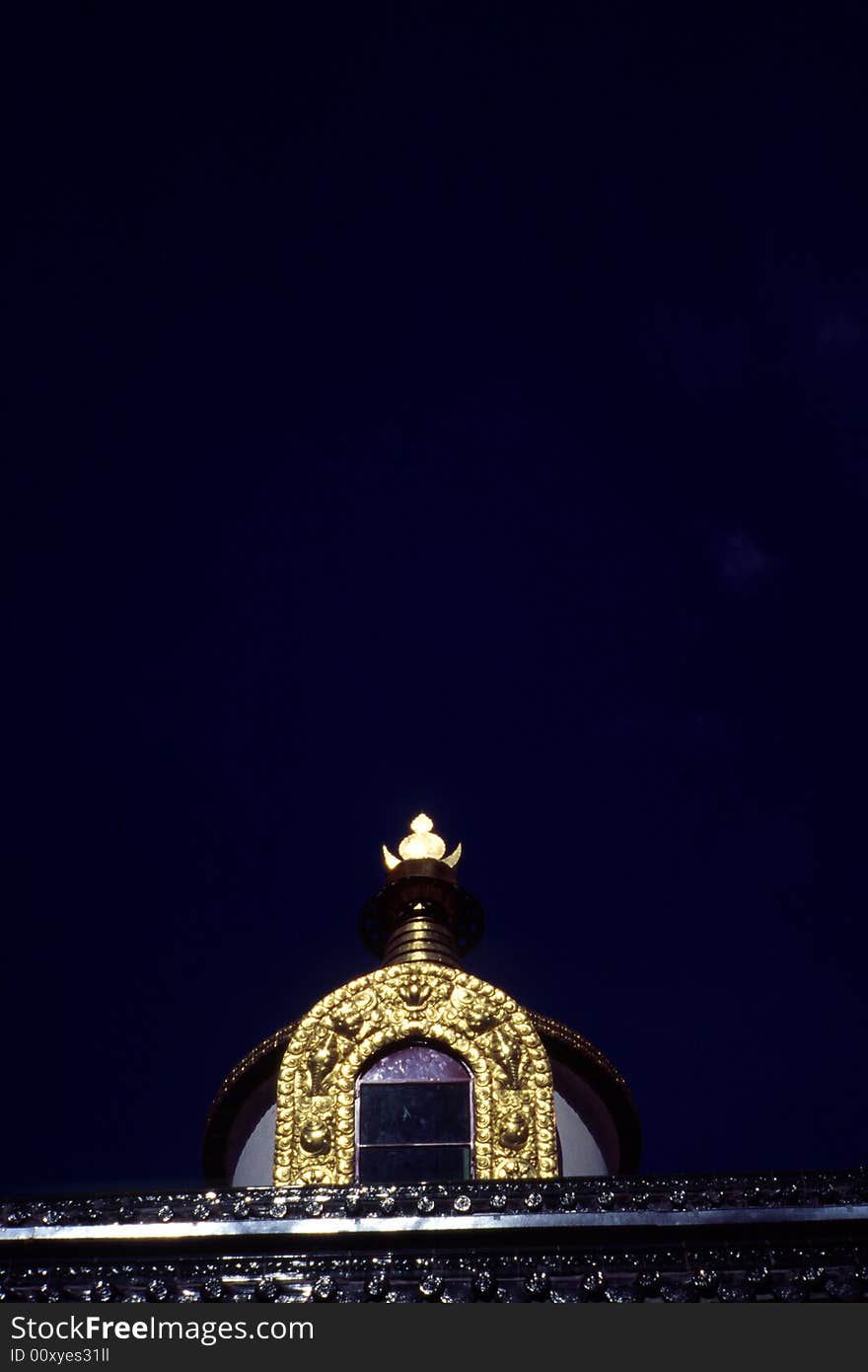 Shining top part of a huge golden pagoda with wonderful craftsmanship in pure dark background