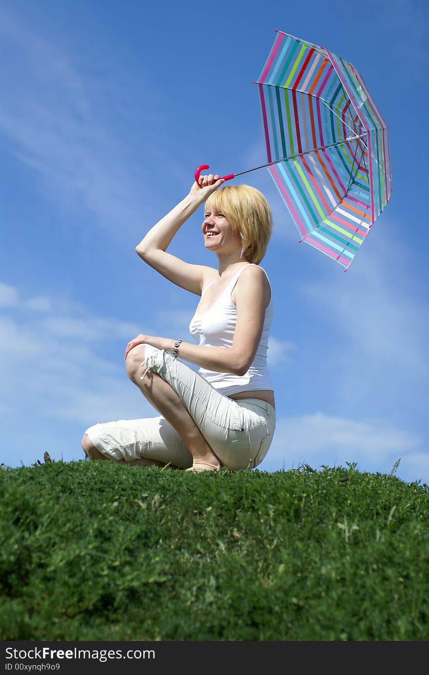 Yong charming girl sitting on the meadow with umbrella. Yong charming girl sitting on the meadow with umbrella