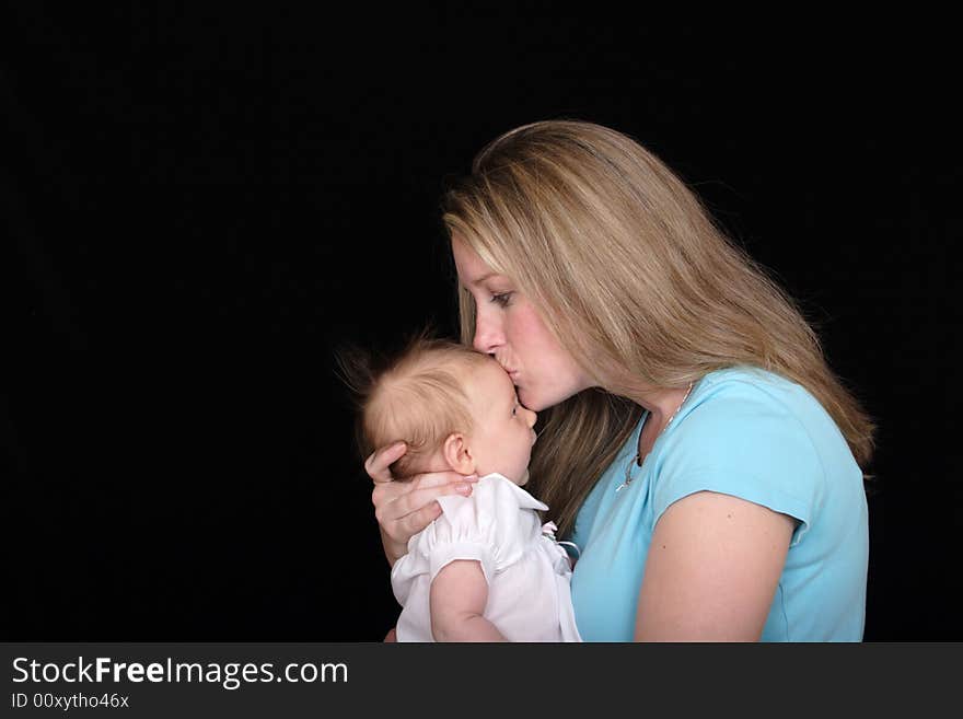 A new mother kisses her baby daughter on the forehead. A new mother kisses her baby daughter on the forehead.