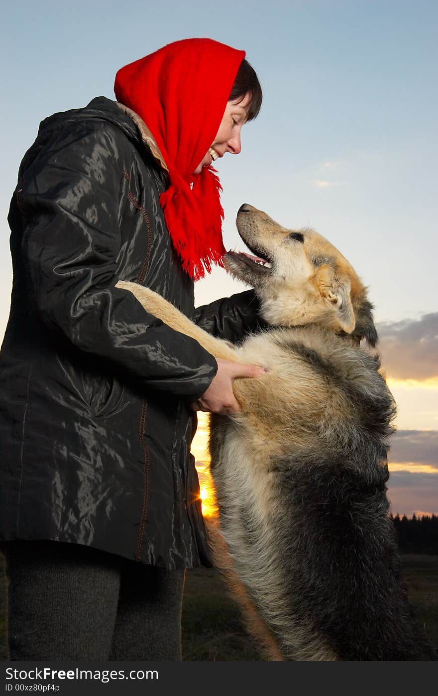 The woman stands with a dog. The woman stands with a dog