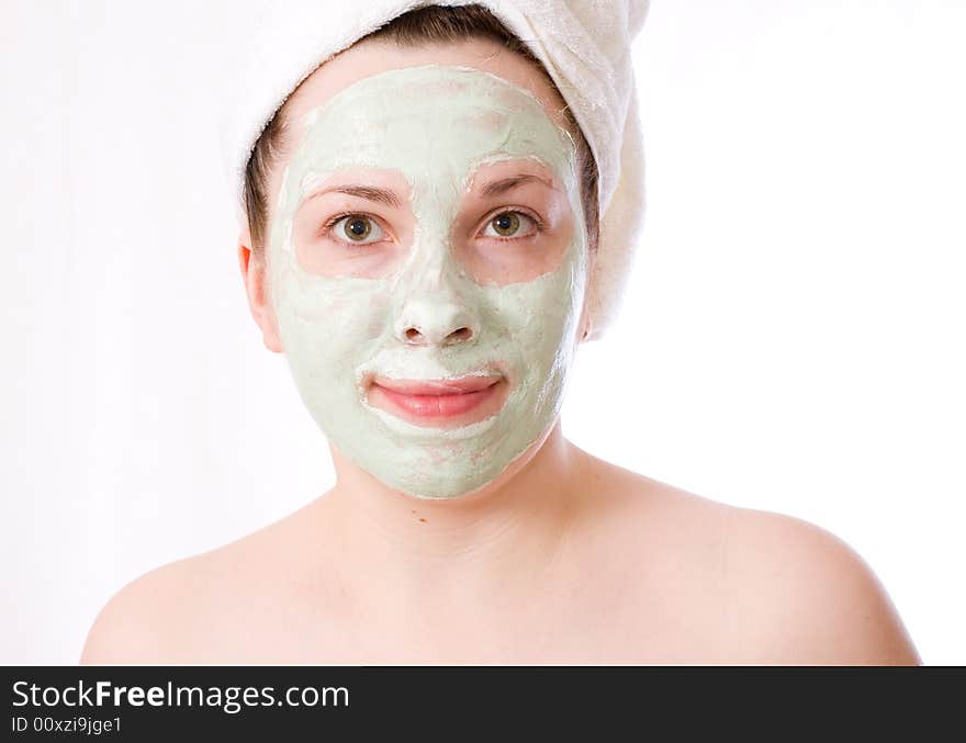 Young woman with green mask on her face healthy treatment, white towel