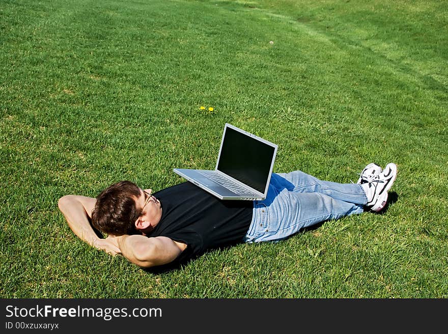 Man lying on the grass with laptop. Man lying on the grass with laptop