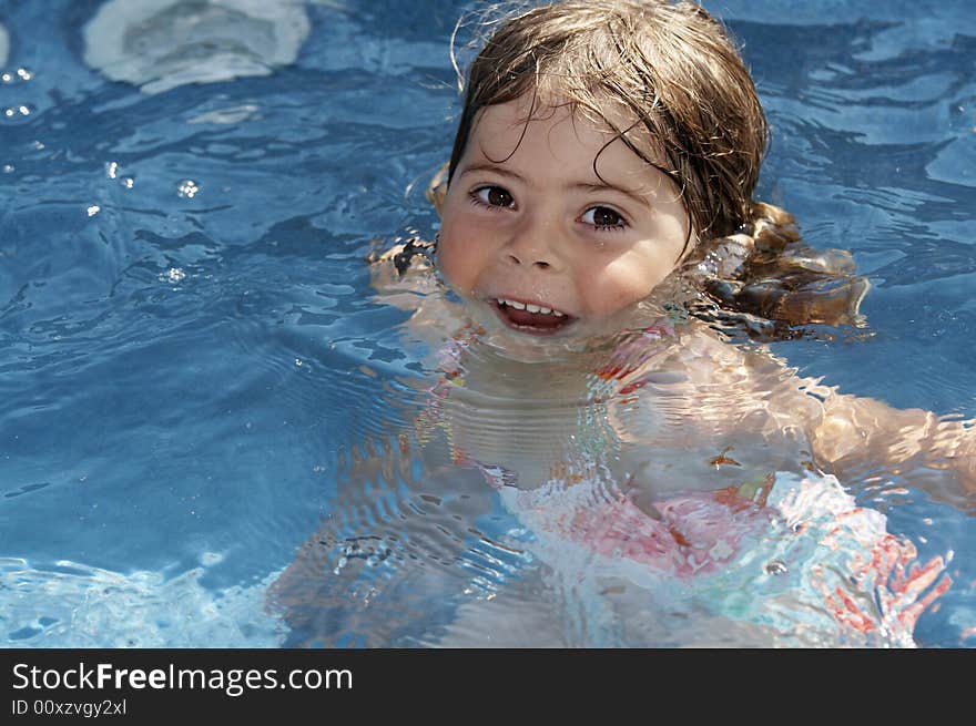 A cute little girl looking at pool water during the summer. A cute little girl looking at pool water during the summer