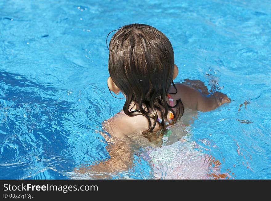 A cute little girl looking at pool water during the summer. A cute little girl looking at pool water during the summer