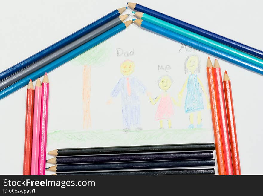 Multicolored pencils at a white paper with a child's family picture. Multicolored pencils at a white paper with a child's family picture