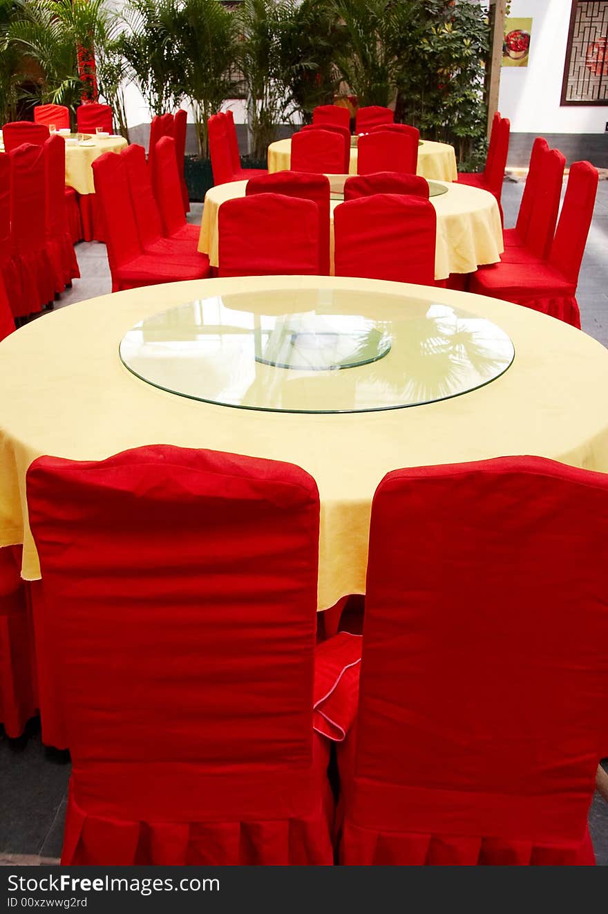 Interior of chinese restaurant with round tables and red chairs.