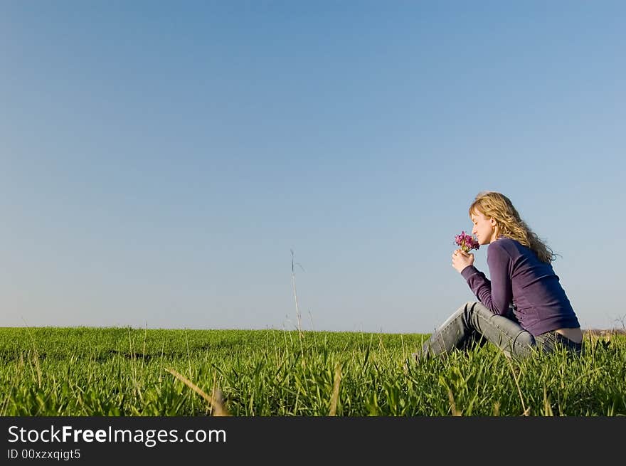 Girl sits on a grass and smells a bunch of flowers. Girl sits on a grass and smells a bunch of flowers