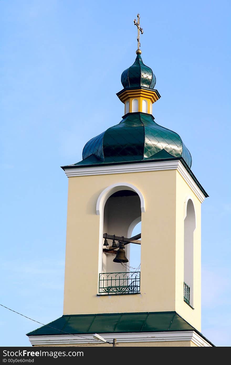 Fragment of church with the bell against the background of the blue sky. Fragment of church with the bell against the background of the blue sky