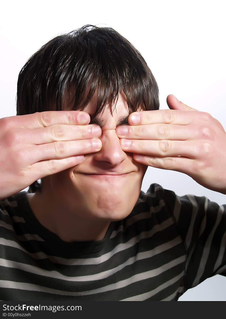 A portrait about a trendy attractive guy who is hiding his eyes with two hands. He is wearing a striped t-shirt. A portrait about a trendy attractive guy who is hiding his eyes with two hands. He is wearing a striped t-shirt.