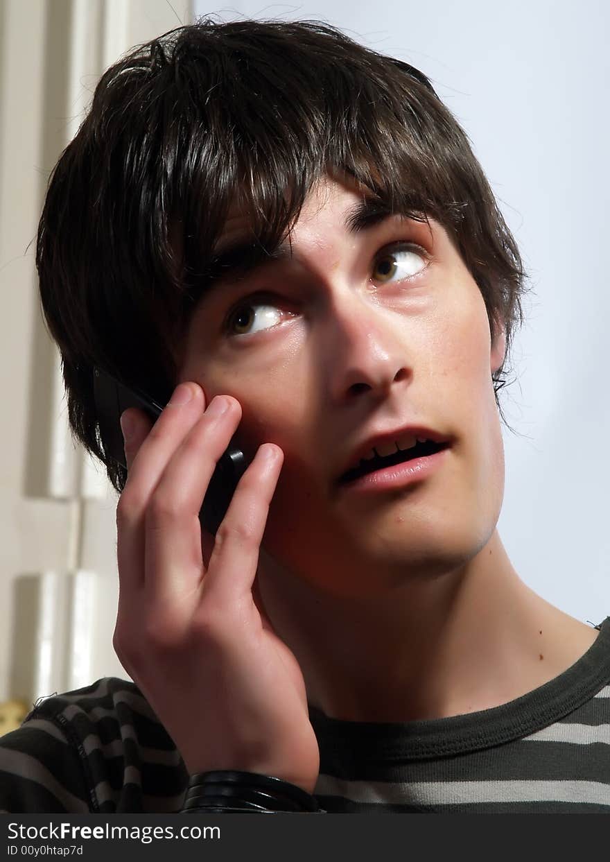 A portrait about a trendy attractive guy who is smiling and he is calling somebody. He is wearing a striped t-shirt. A portrait about a trendy attractive guy who is smiling and he is calling somebody. He is wearing a striped t-shirt.