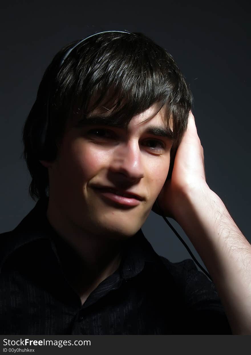 A portrait about a trendy handsome young guy who is smiling and he is listening to music. He is wearing a stylish black shirt. A portrait about a trendy handsome young guy who is smiling and he is listening to music. He is wearing a stylish black shirt.