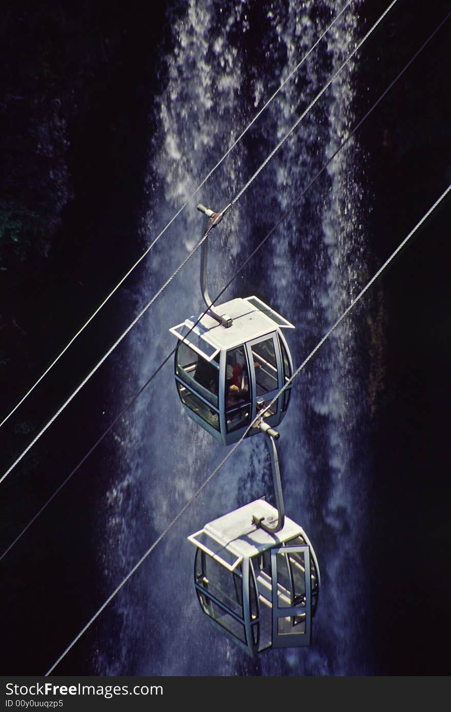 Two cable cars passing by a waterfall, jiangxi, china