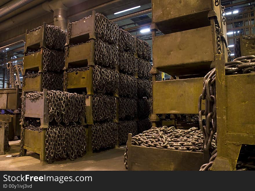 Many boxes with chains, inside a chain factory.