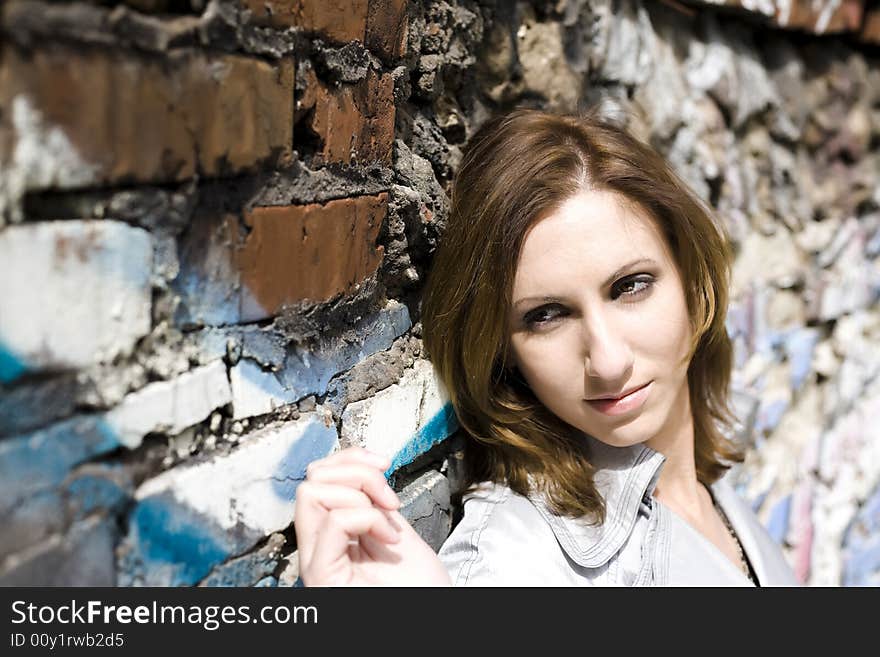 Beautiful brunette standing near the grunge wall. Beautiful brunette standing near the grunge wall