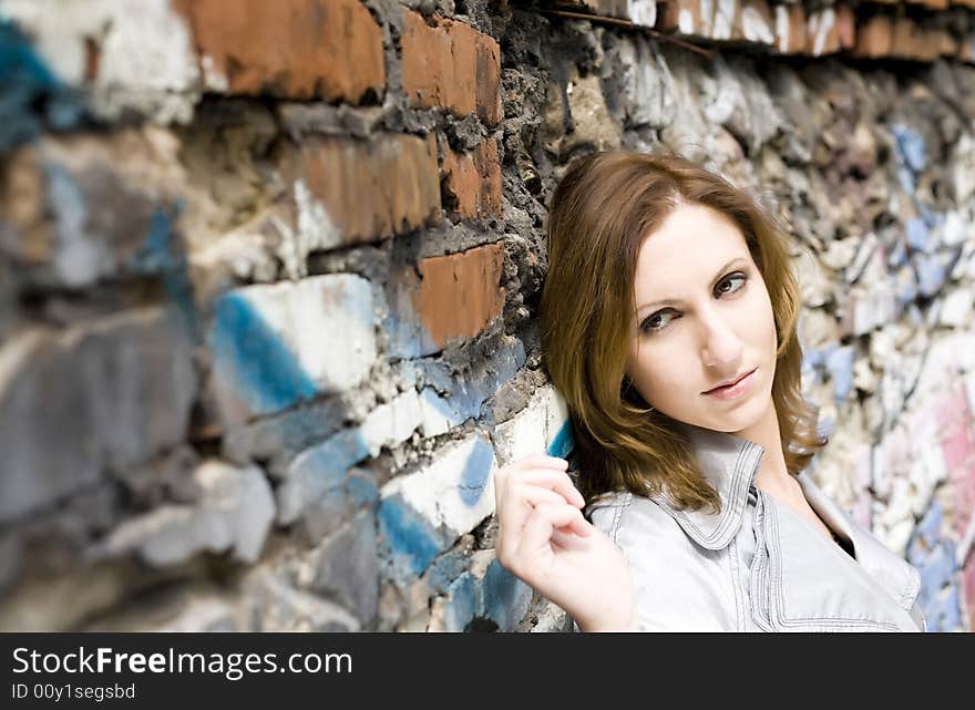 Close-up of an attractive young woman leaning against a graffiti painted wall. Close-up of an attractive young woman leaning against a graffiti painted wall