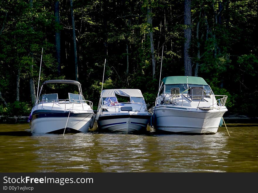 Three pleasure boats anchored next to each other.