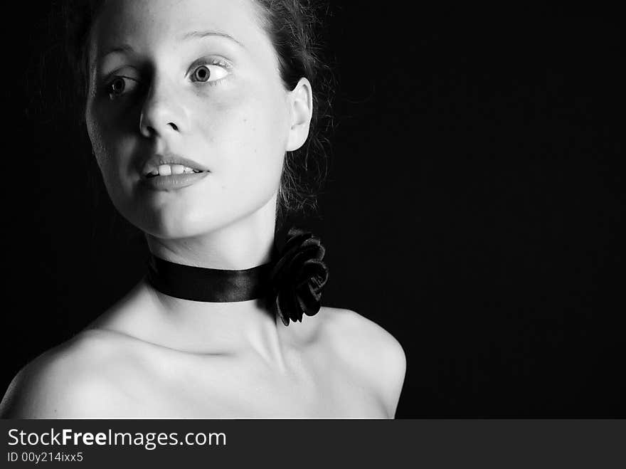 Portrait of the beautiful naked girl with an ornament on a neck on a black background. Portrait of the beautiful naked girl with an ornament on a neck on a black background