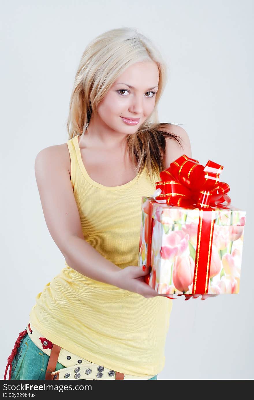 Smiling blond dressed in yellow shirt with big gift box in hands. Smiling blond dressed in yellow shirt with big gift box in hands