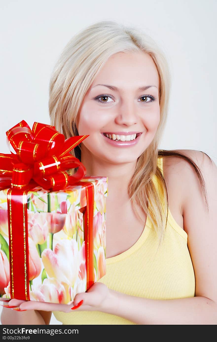 Smiling blond dressed in yellow shirt with big gift box in hands. Smiling blond dressed in yellow shirt with big gift box in hands