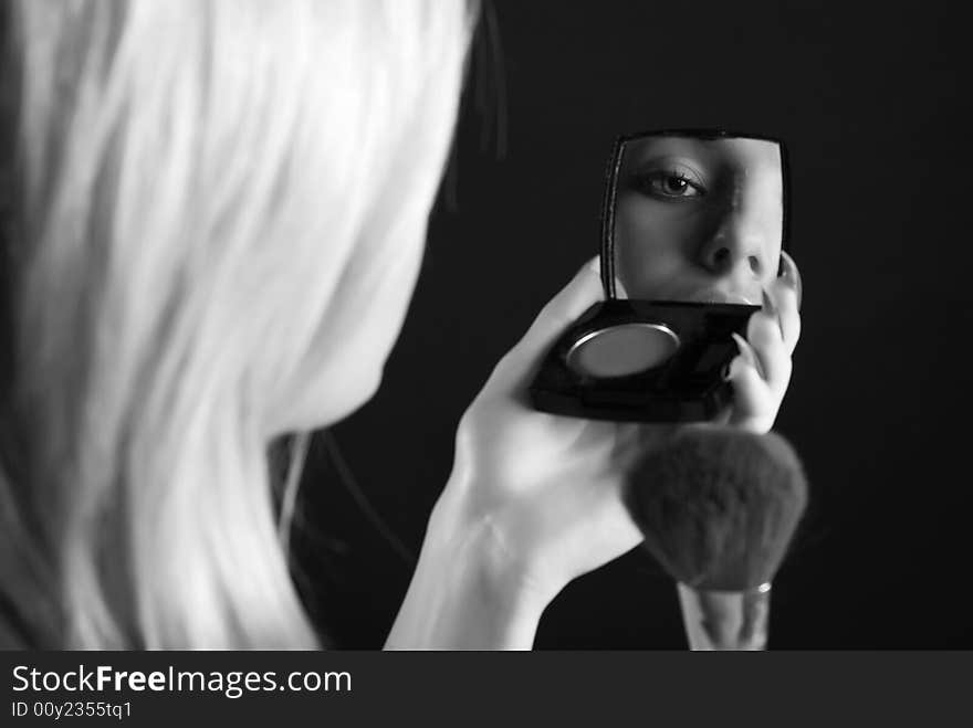 The young girl looks in a small mirror and makes up. The young girl looks in a small mirror and makes up