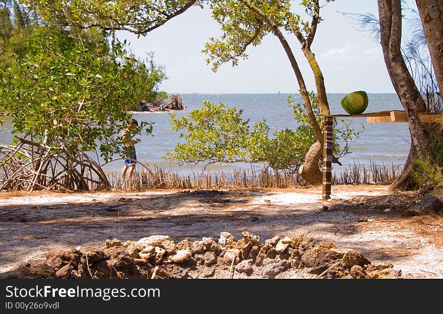 Tropical campsite on water with young boy exploring in background. Tropical campsite on water with young boy exploring in background