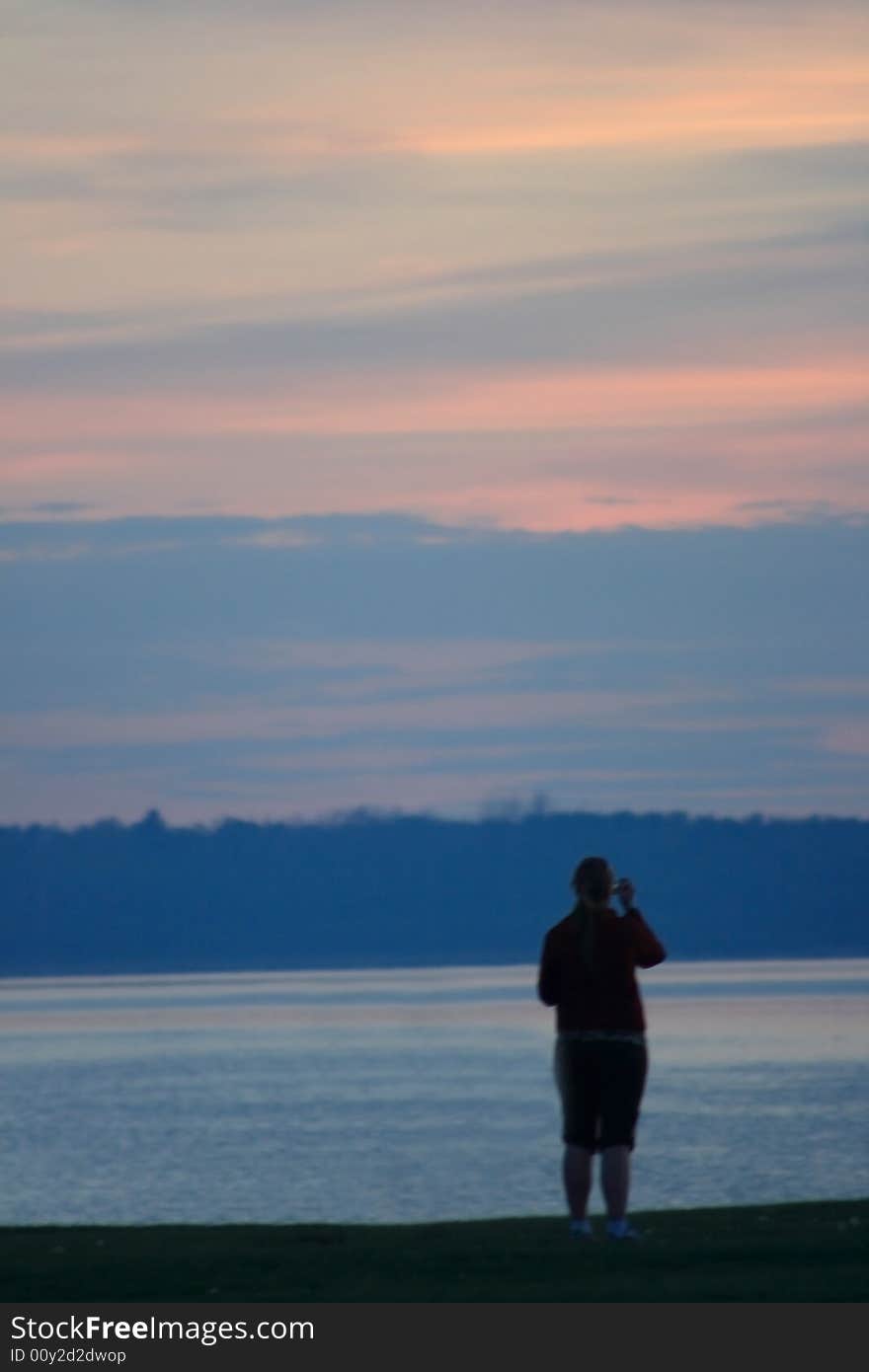 Soft Focus sillhouette of a person in quiet contemplation on the shore of a lake at Sunset. Soft Focus sillhouette of a person in quiet contemplation on the shore of a lake at Sunset