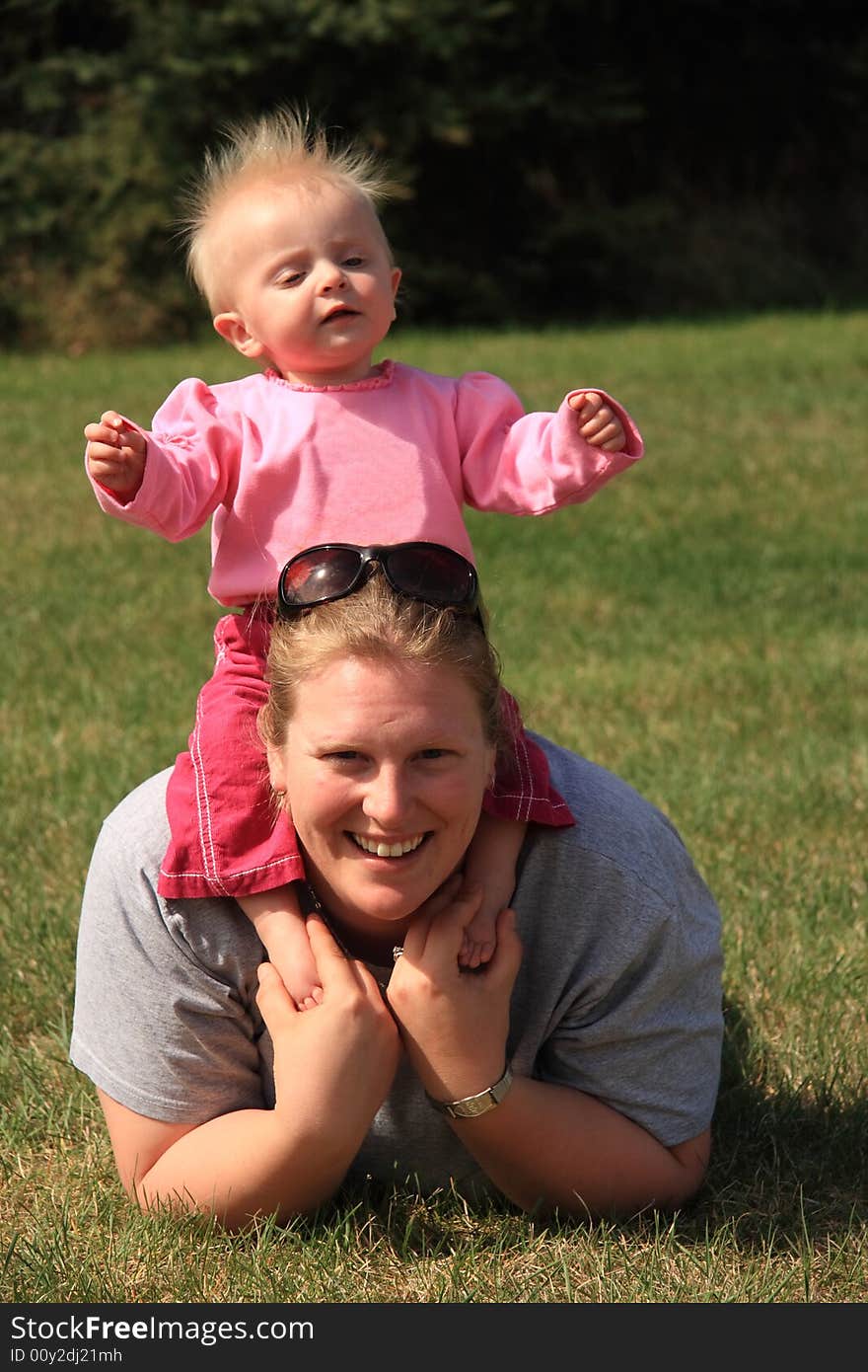 A young mother enjoying a summer day at the park with her young daughter. A young mother enjoying a summer day at the park with her young daughter