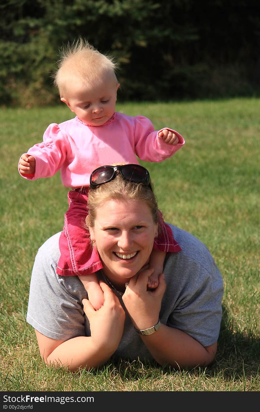 A young mother enjoying a summer day at the park with her young daughter. A young mother enjoying a summer day at the park with her young daughter