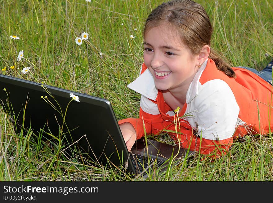 Girl lies on a grass on to the meadow and works with a notebook. Girl lies on a grass on to the meadow and works with a notebook