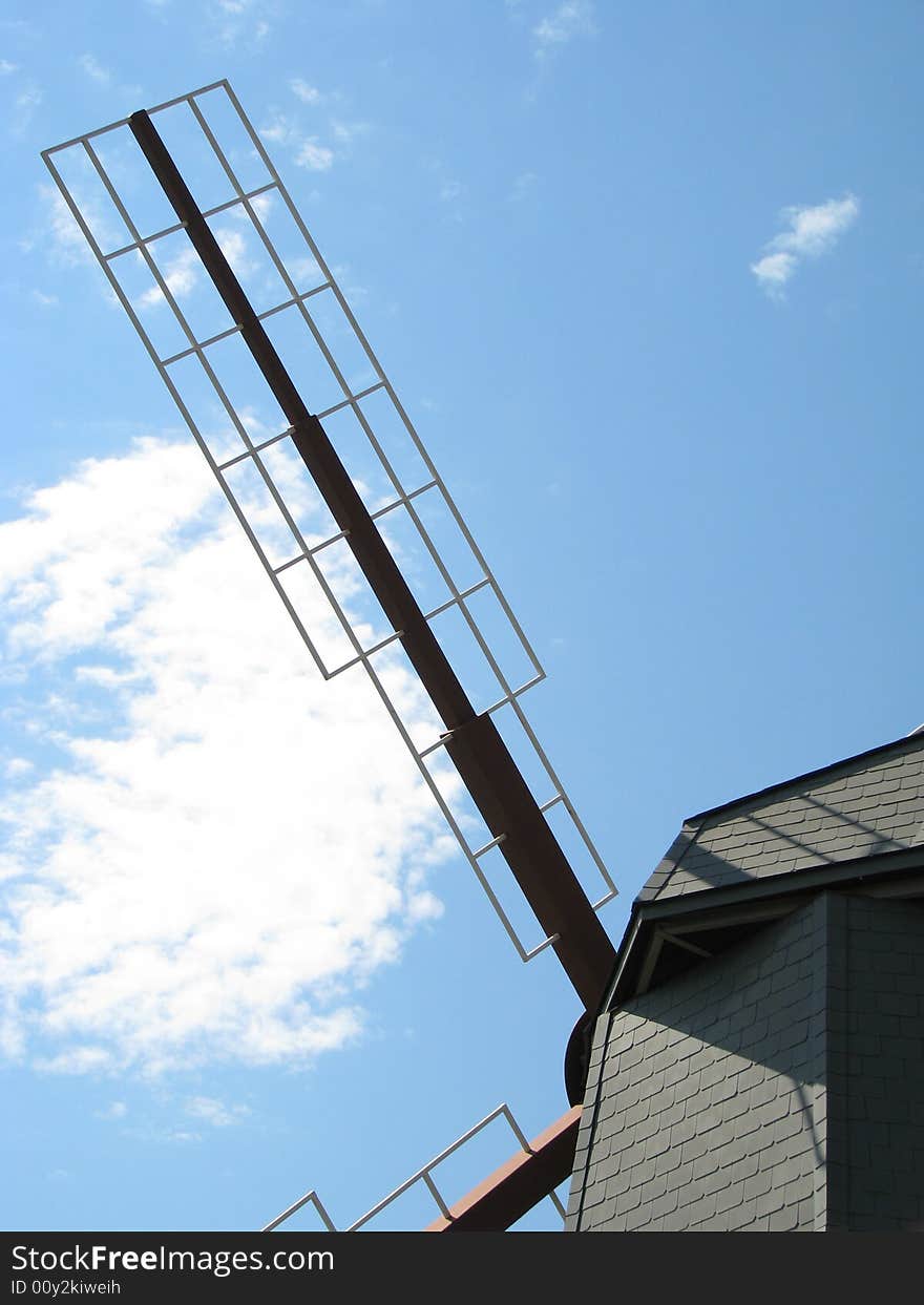 Windmill arm stretching out into a cloud spattered sky.