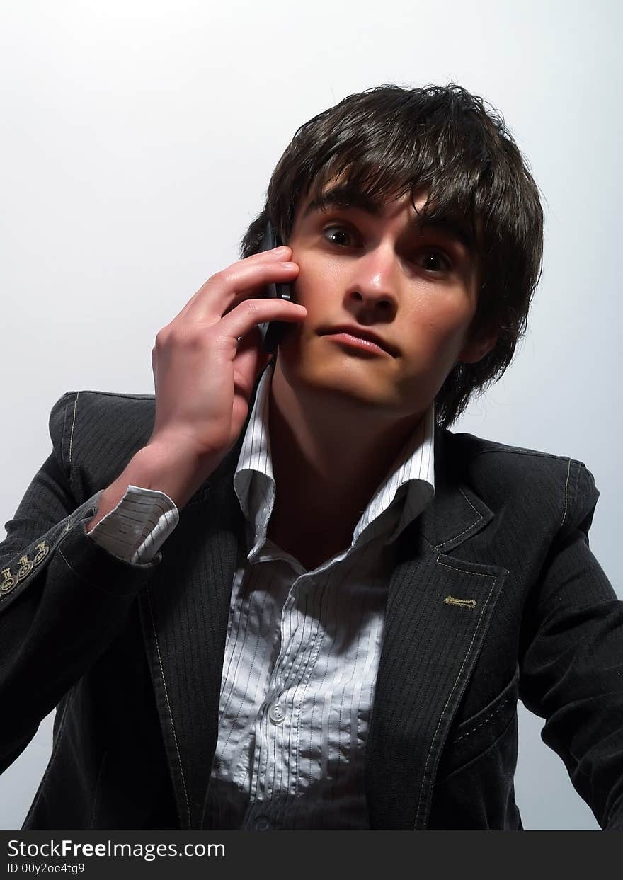 A portrait about a trendy handsome guy who is calling somebody and he is surprised. He is wearing a white shirt and a stylish black suit. A portrait about a trendy handsome guy who is calling somebody and he is surprised. He is wearing a white shirt and a stylish black suit.