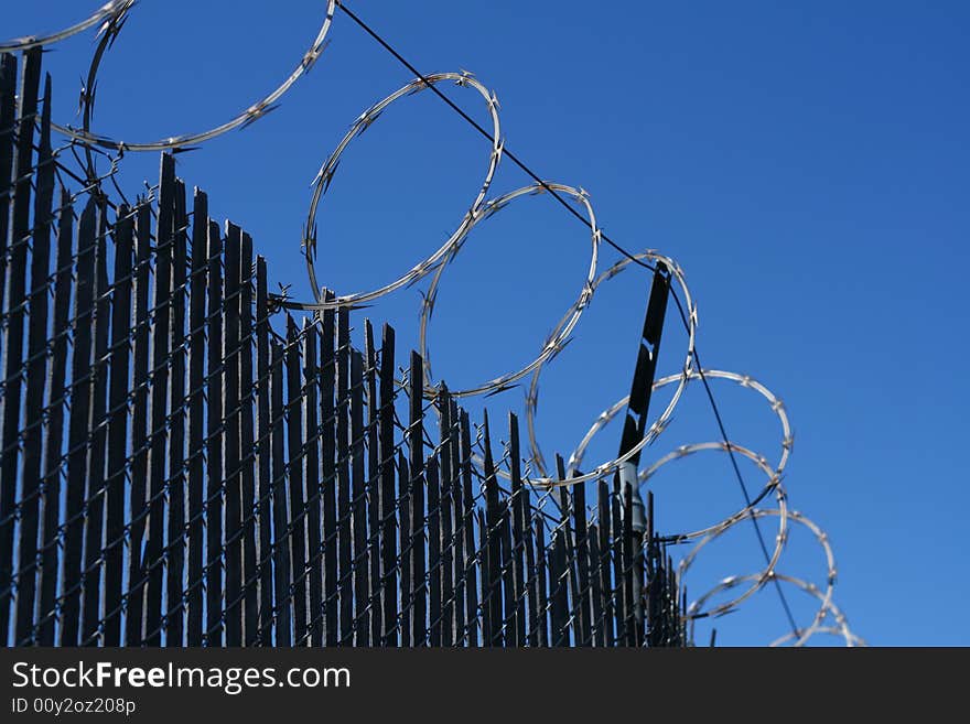 A worms eye view of a barbed wire fence in front of a blue sky.